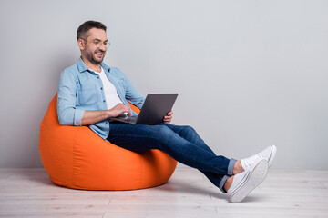 Portrait of his he nice attractive focused cheerful cheery content gray-haired guy using laptop...