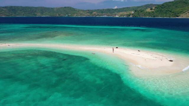Wonderful Exotic Nature of Philippines Islands. Orbit Aerial View of Man Walking on Sandbar With Turquoise Sea and Traditional Filipino Boat