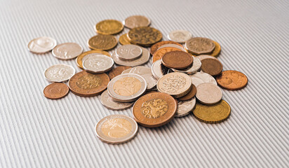 Many different coins from different countries from the black wallet are scattered around the table: dollars, pounds, rubles, pennies, cents, yuan. Saving money, losing finance, earning.