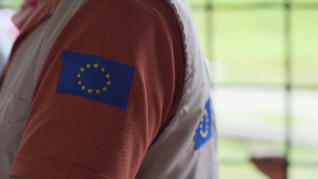 Flag of Europe in volunteer uniform talking, helping in rural communities