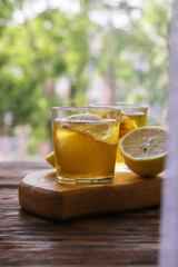 Cold kombucha with lemon in glasses on wooden background. Summer fermented raw tea