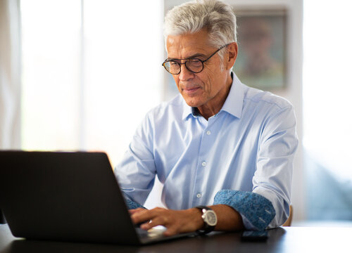 Older Businessman Working From Home With Laptop Computer