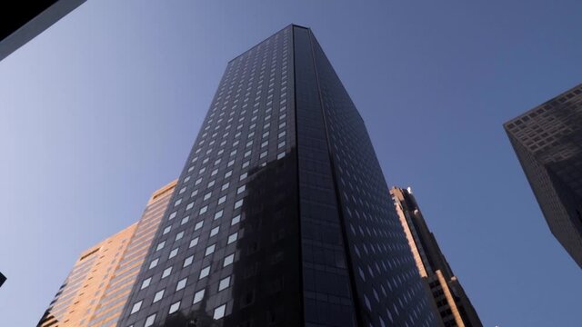 Up view of black Manhattan Skyscraper in slow motion during sunny weather with no clouds in New York City.