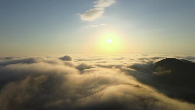 Drone fly over the sea of clouds with mountain landscape hill peak and sunshine during a sunrise with the sun up to the blue sky. Near Death Experience aerial footage concept