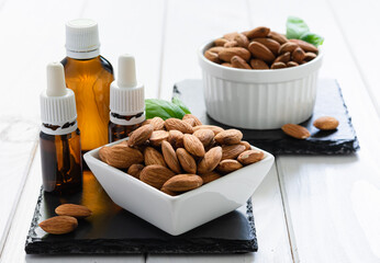 almonds in a white plate and glass bottles with oil on a black tray on a wooden table