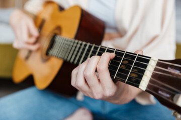Fototapeta premium Image closeup of young caucasian woman playing acoustic guitar at home