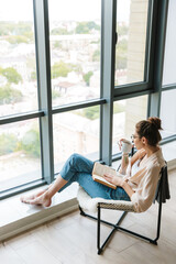Image of thinking cute woman reading book and drinking coffee