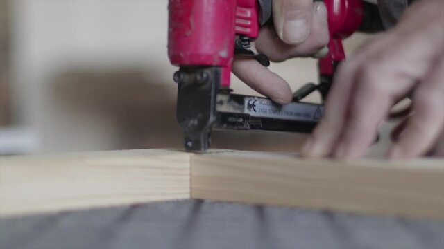 Hydraulic stapling gun staples wooden planks together. Carpenter's shop. Professional carpenter.