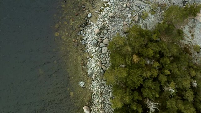 Aerial, top down, drone shot above over the shallow water and rocky coast ofa island in the archipelago of Porvoo, cloudy day, in Uusimaa, Gulf of Finland
