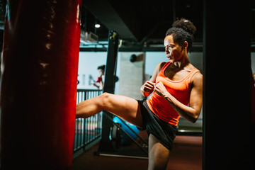 Beautiful fit woman in sportswear boxing kicking bag in the gym.
