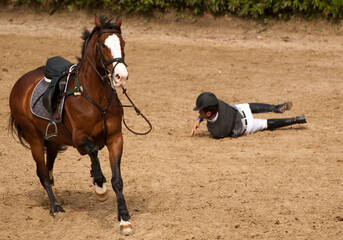 Rider falling down from a jumping horse on a tournament