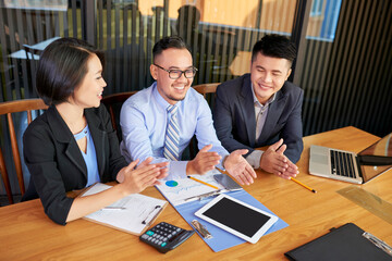 Group of three business people clapping their hands after listening to their colleague during meeting, high anlke shot