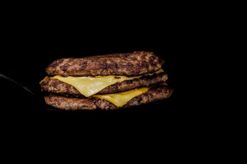 Isolated meat for burger with cheese on dark background. Meat for burger with black background. Meat for bufger with double cheese. Isolated meat for burger with dark background. Fast food. Burger.