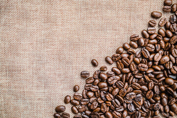 Brown dark roasted coffee beans on old bag background. Photos from the top view and copy space. Seed nature from the above view. Group agriculture grain arabica.