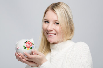 Smiling young woman with her colorful piggy bank