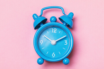 Blue alarm clock on a pink background, top view