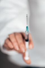 Close-up image of female doctor's hand with a syringe.