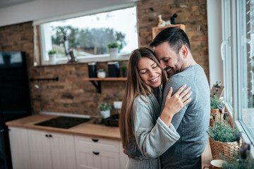 Affectionate couple standing in the kitchen and hugging.
