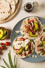 Mini tortillas with tomato salsa, avocado and boiled chicken. Top view.