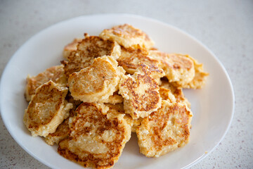round fried golden curd cheesecakes on a white round plate, white background