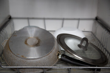 grey steel pan with glass lid on metal rack of dish dryer