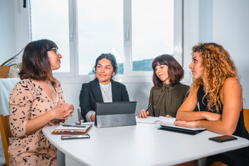 Session young entrepreneurs in the office, young man of Latin ethnicity and three young Caucasian women in a table meeting