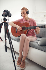 Obraz na płótnie Canvas Guitarist making video lessons and tutorials for internet vlog website classes.