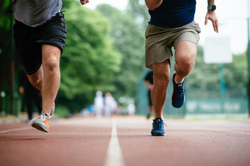 Fototapeta premium Young men training on a race track. Two young friends running on athletics track