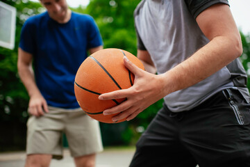 Close up of hands holding ball. Friends playing basketball in the park.