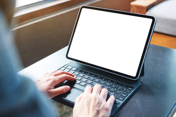 Mockup image of a woman using and typing on tablet keyboard with blank white desktop screen as a computer pc on the table