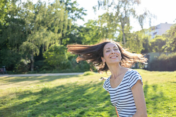 Naklejka premium Young caucasian woman in the park with flying hair