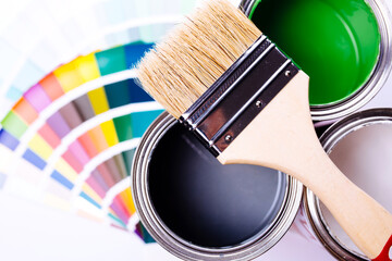 Paint brush laying on a heap of color samples. open can of green paint