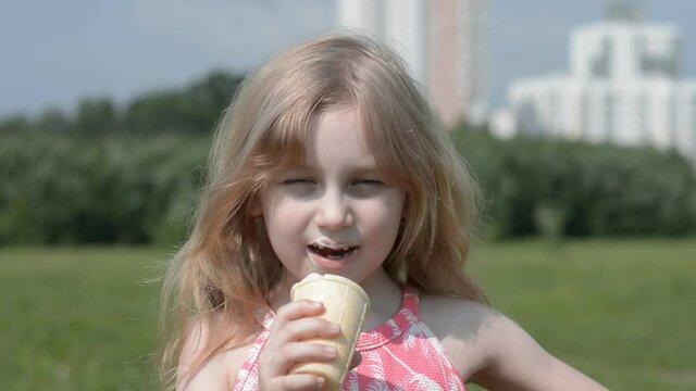 Caucasian little girl five years old eat ice cream in a summer park  hd