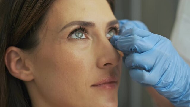 A close-up view of a professional doctor-cosmetologist is doing a face-care procedure to woman client in beauty salon
