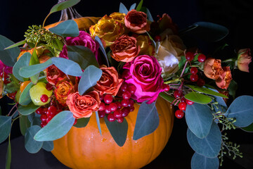 Bouquet of flowers in a pumpkin as in a vase on a black background