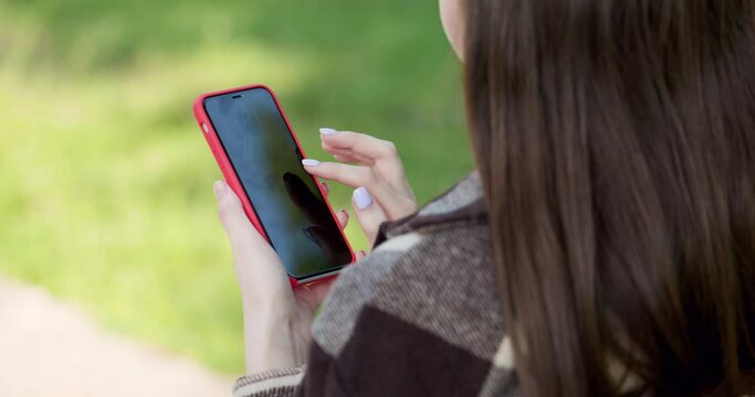 Close up Young girl using mobile smart phone in the park. Internet, using smartphone, close-up fashion model, post in instagram, facebook concept