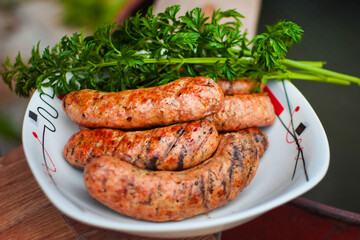 Appetizing grilled bavarian sausages on a white plate with parsley and dill.