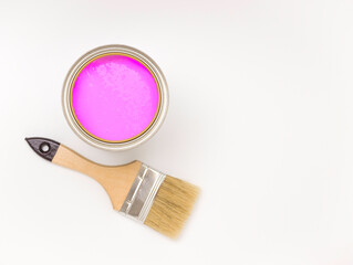 Tools for construction and decoration. Paintbrush next to a can of pink paint on a white background, top view, free space for text.