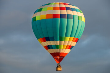 Colorful big hot air balloon flying against the cloudy sky
