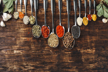 Spices in spoons on dark wooden background top view