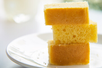 Close up stack of butter cake in a white plate on white table with a cup of milk blurred background.