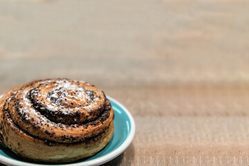 Brownish bun with poppy seeds on a wooden table