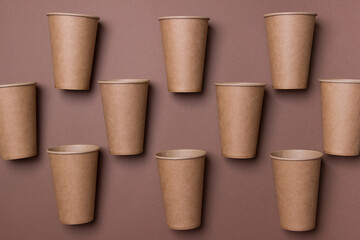 group of brown eco-friendly cardboard cupd lie on brown colored paper background in chessboard order., top view, close up. mock up