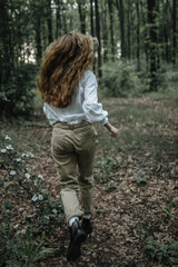 Girl with long hair runs away in the forest.