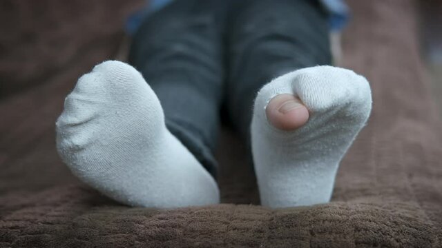 Poverty. Child's feet with holes in socks.
