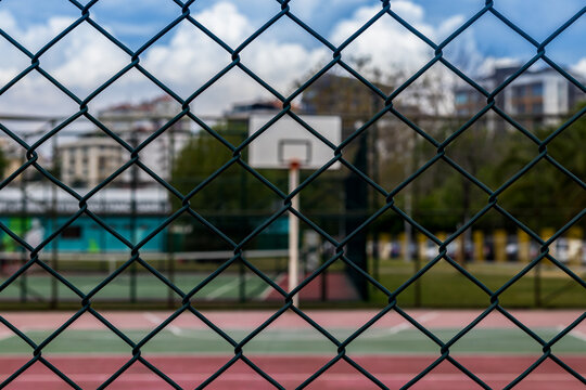 green wire netting and basketball coart with hoop and city unfocused view. outdoor sport theme