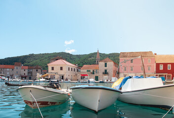Waterfront view of old simple boats docked in the harbour of Starigrad, Hvar. City square in the...