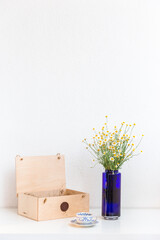 Bouquet of daisies in a blue vase with vintage tea cup and wooden box on white background.  Still-life. With copy space.
Cup of aromatic tea with a camomile flowers. Place for text. 