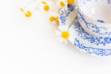 Bouquet of daisies and vintage tea cup on white background.  With copy space.
Cup of aromatic tea with a camomile flowers. Place for text. 