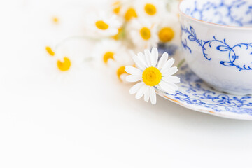 Bouquet of daisies and vintage tea cup on white background.  With copy space.
Cup of aromatic tea with a camomile flowers. Place for text. 